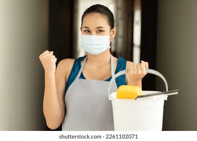 Happy smiling successful Asian immigrant cleaning service worker woman, concept image of domestic helper holding cleaning supplies, ready for work