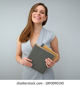 Happy smiling teacher wearing grey dress holding books. Isolated female portrait.
