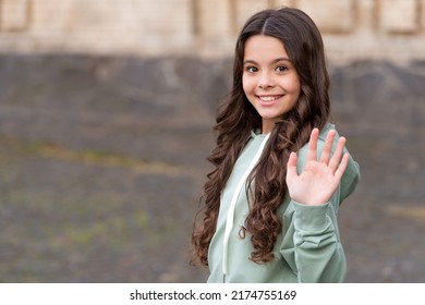 Happy Smiling Teen Girl In Casual Waving Hand Making Hello Or Goodbye Gesture, Copy Space