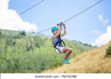 Happy smiling teen girl riding a zip line ride while on family vacation - Shutterstock ID 746742388