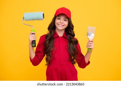 Happy Smiling Teenager Girl Builder In Building Uniform And Cap. Painter With Painting Brush Tool Or Paint Roller. Worker Isolated On Yellow Background. Kids Renovation Concept.