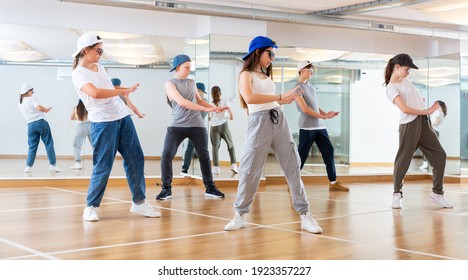 Happy Smiling Teenagers Practicing Vigorous Hip Hop Movements In Dance Class