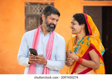 Happy Smiling Traditional Indian rural farmer couple using smart phone to make online payment while looking at each other, shopping on internet with cellphone secure banking service system concept. - Shutterstock ID 2097450274