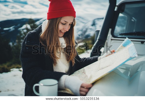 Happy smiling traveler girl exploring map\
outdoor traveling by authentic car, lifestyle adventure concept,\
woman searching new direction on map enjoying vacation,mountains\
landscape on background