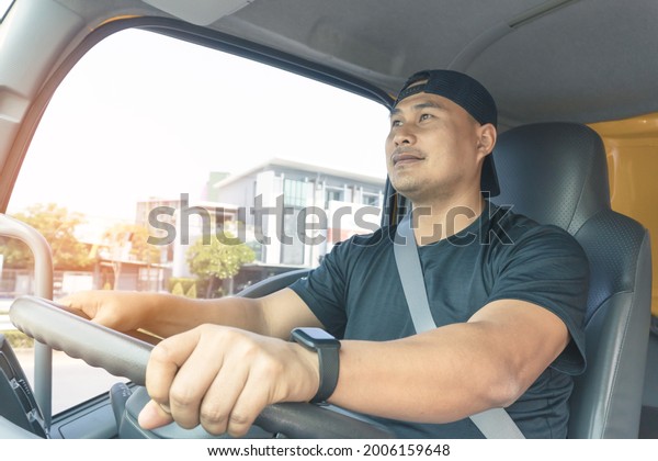 happy smiling truck driver bearded male\
fastens his seat belt while driving. Delivery Man Transport with a\
semi-truck, trustworthy, friendly\
service.