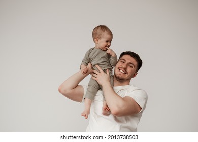 A happy, smiling uncle spends time with his niece, playing and holding the baby on his shoulder, gently supporting her. The baby smiles and holds a finger in his mouth - Shutterstock ID 2013738503