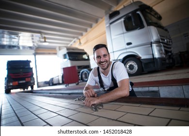 Happy Smiling Vehicle Mechanics Holding Wrench Tools In Truck Repair Workshop. Trucks Freighter In Background.