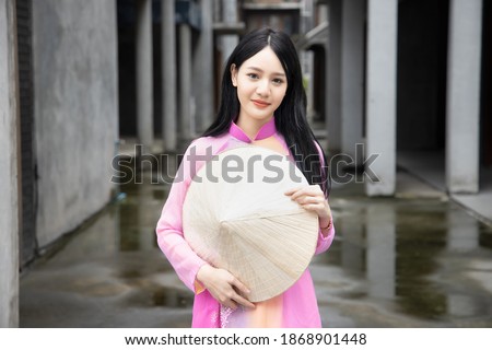 Happy smiling Vietnamese girl; portrait of exotic asian Vietnam woman in traditional Vietnamese Ao Dai dress