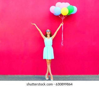 Happy smiling woman with an air colorful balloons over a pink background - Shutterstock ID 630899864