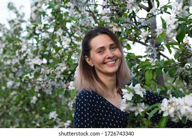 Happy smiling woman among blooming branches looking at the camera, spring time - Shutterstock ID 1726743340