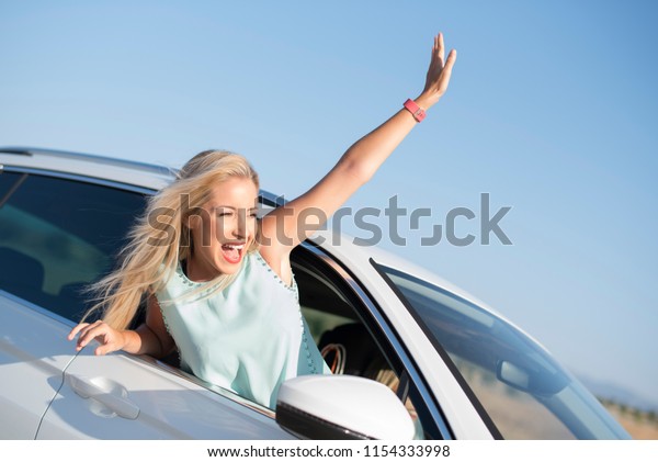 Happy smiling woman in car very happy out of\
window with funny\
expression