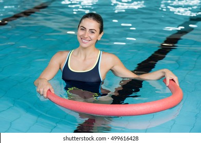 Happy Smiling Woman Doing Exercise With Aqua Tube In A Swimming Pool. Young Sportive Woman Exercising In Swimming Pool With The Help Of A Tube. Young Heallthy Woman Doing Aerobics In Swimming Pool.
