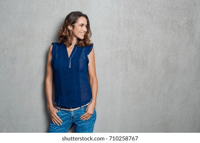 Happy Smiling Woman Dressed In A Blue Dress Isolated On Grey Background. Mature Woman Looking Away Against Grey Background. Beautiful Woman In Casual Thinking With Copy Space.