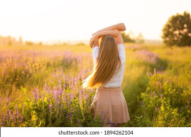 Happy Smiling Woman On A Purple Field At Sunset, Freedom Concept. High Quality Photo