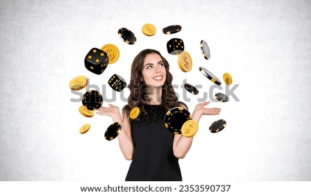 Happy smiling woman with open hand palms, looking at falling dollar coins and dice with poker chips on grey concrete wall background. Concept of jackpot, luck and success