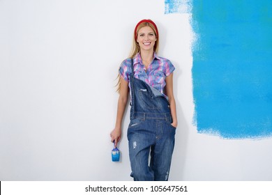 Happy Smiling Woman Painting Interior White  Wall In Blue And Green Color Of New House