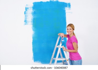 Happy Smiling Woman Painting Interior White  Wall In Blue And Green Color Of New House