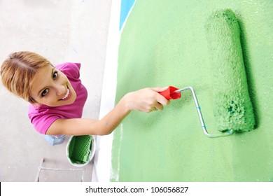 Happy Smiling Woman Painting Interior White  Wall In Blue And Green Color Of New House