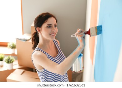 Fröhliche lächelnde Frau, die Innenwand des neuen Hauses gemalt. Fröhliche lächelnde Frau