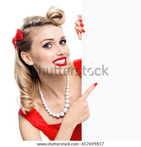 Happy smiling woman in pin-up style dress, showing blank signboard with copyspace, isolated over white background. Caucasian blond model posing in retro fashion and vintage concept studio shoot.