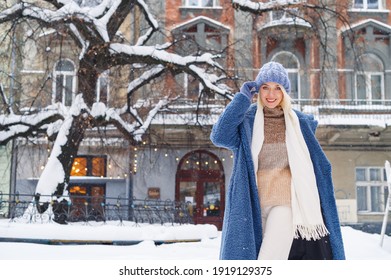 Happy smiling woman posing in street of European city. Model wearing blue faux fur coat, hat, white scarf. Winter, Christmas, New Year holidays, travel conception. Copy, empty space for text - Powered by Shutterstock