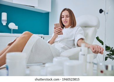 Happy smiling woman sitting in medicine armchair during medical procedure in beauty center
