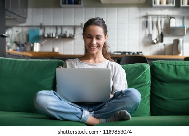 Happy smiling woman sitting on sofa, couch and using laptop at living room at home, watching funny video, learning language, video calling, mother working online - Powered by Shutterstock