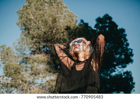 Similar – Kühle blonde Frau mit Sonnenbrille und schwarzem Kleid, die sich bei Sonnenuntergang in der Natur amüsiert.