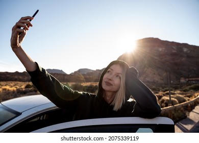 Happy smiling woman taking selfie using smartphone, enjoying a car road trip along the mountainous landscape, off-road trip. Traveler. Real people lifestyle.
 - Powered by Shutterstock