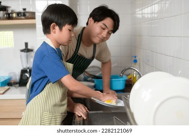 Happy smiling Young Asian father and son washing dishes in kitchen at home  - Powered by Shutterstock