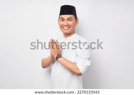 Happy smiling young Asian Muslim man in Arabic costume standing with gesturing Eid Mubarak greeting and welcoming Ramadan isolated on white background. People religious Islamic lifestyle concept