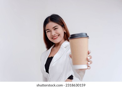 A happy and smiling young asian woman holding a coffee cup and posing to the camera. Isolated on a white background.