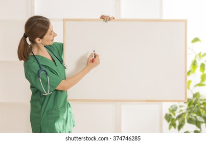 Happy smiling young beautiful female doctor showing blank area for sign or copy space. Nurse showing blank clipboard sign - medical concept