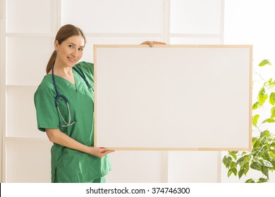 Happy smiling young beautiful female doctor showing blank area for sign or copy space. Nurse showing blank clipboard sign - medical concept