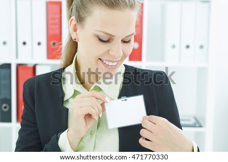 Happy smiling young business woman wearing blank badge. Name tag on chest. Person identity label. Business card mock-up.