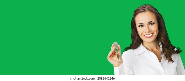 Happy smiling young businesswoman or real estate agent showing keys from new house. Portrait of brunette woman at studio, green colour background with copy space area for text. Chroma key back - Shutterstock ID 2092642246
