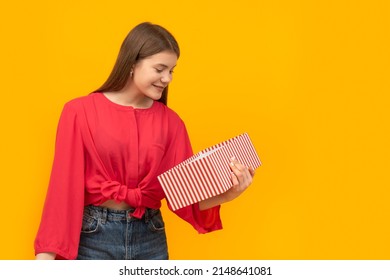 Happy And Smiling Young Girl With Gift Box In Her Hands. Unexpected Gift. Yellow Background