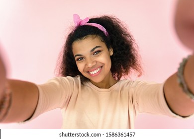 Happy smiling young hipster african american teen girl blogger mixed race woman vlogger take selfie record vlog look at mobile camera isolated on pink studio background, portrait, phone cam view - Powered by Shutterstock