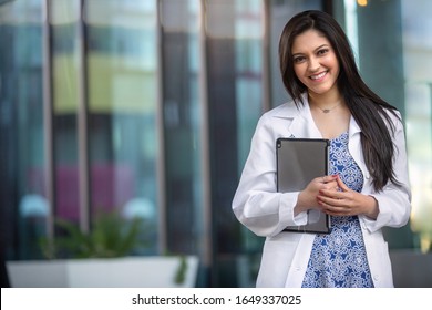 Happy smiling young Indian american professional in the medical field, possibly dental, therapy, medicine, doctor, with computer