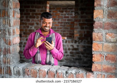 Happy Smiling Young Indian Labour Busy On Mobile Phone At Workplace - Concept Of Using Social Media Application, Technology And Leisure Activity.