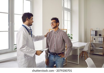 Happy, smiling young man talking to his doctor. Qualified specialist at a modern clinic, hospital or medical center reassuring his male patient after a consultation and health checkup
