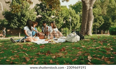 Happy smiling young multinational people at picnic on summer day outdoors. Friends have fun weekend together, relaxing in the park at picnic