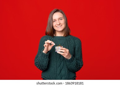 Happy Smiling Young Woman Holding Small Gift Box Over Red Isolated Studio Background