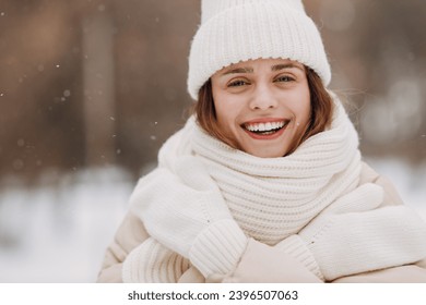 Happy smiling young woman portrait dressed coat scarf hat and mittens enjoys winter weather at snowy winter park - Powered by Shutterstock