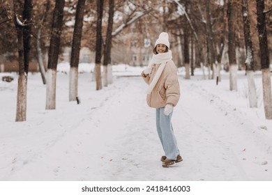 Happy smiling young woman portrait dressed coat scarf hat and mittens enjoys winter weather walking at snowy winter park - Powered by Shutterstock