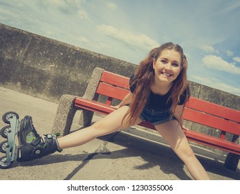 Happy smiling young woman wearing roller skates outdoor. Girl having fun resting on bench.
