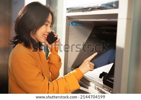 Happy smiling young woman withdrawing money from credit card. Young woman typing pin code on keypad of ATM machine.