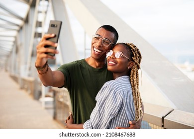 Happy smilng couple taking selfie with phone outdoors. Boyfriend and girlfriend having fun outdoors	
