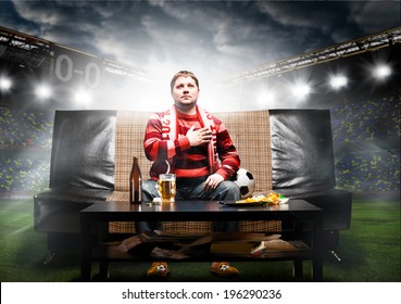 Happy Soccer Or Football Fan With Hand On Heart On Sofa At Stadium