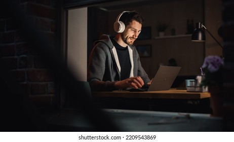 Happy Software Developer Working on a Laptop. Cheerful Information Technology Specialist Wearing Headphones, Listens to Music, Does Professional Work. Remote Job at Home Office Concept.